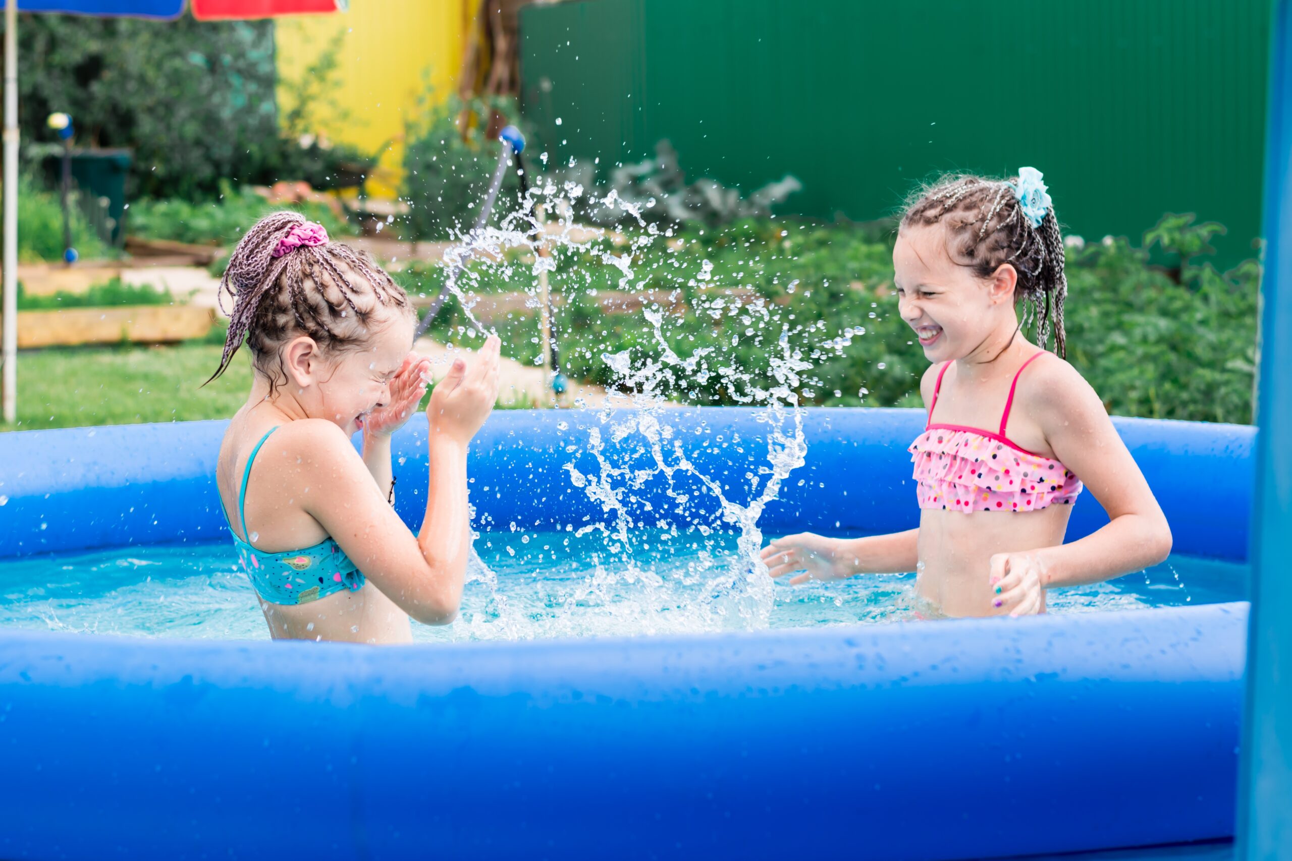 Two,Girls,Have,Fun,Splashing,In,An,Inflatable,Pool,On